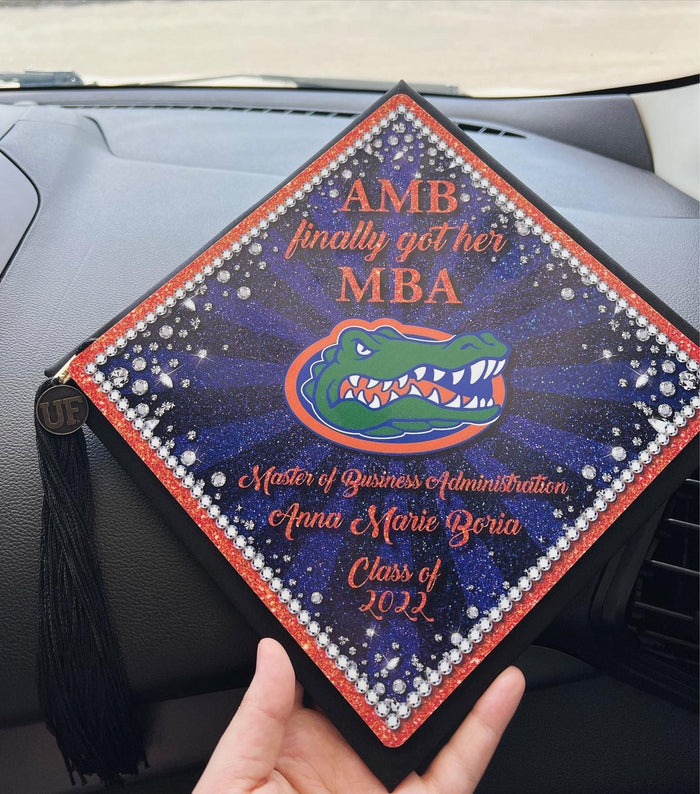 Hands holding Florida Gators MBA cap in car