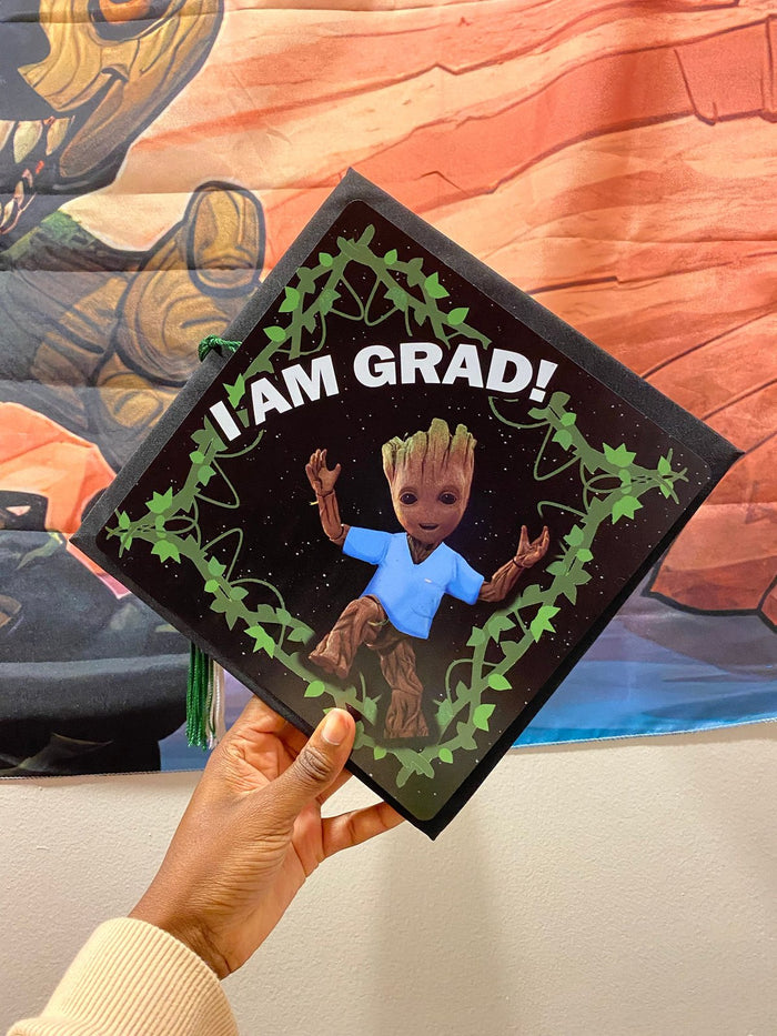 Hand holding Groot I Am Grad cap