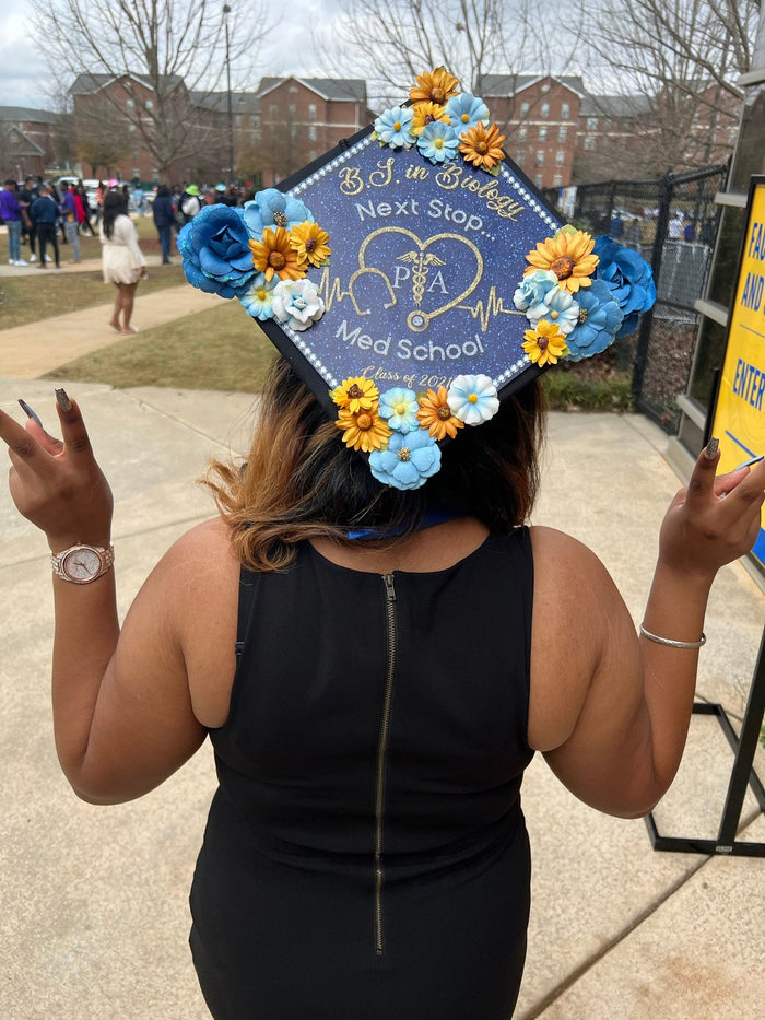 Woman wearing flower Next Stop Med School cap, back view