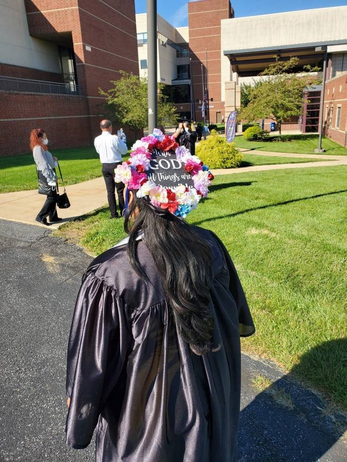 Graduate wearing flower-ringed With God cap on campus