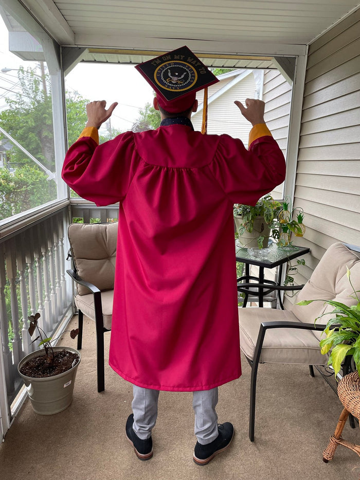 Child in red gown wearing Navy cap on porch