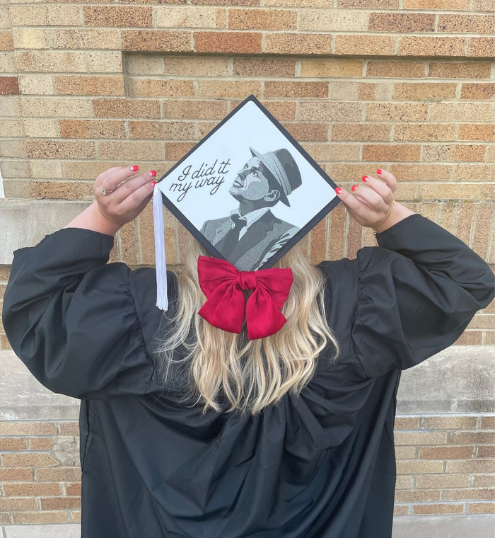 Graduate holding Sinatra I Did It My Way cap over head