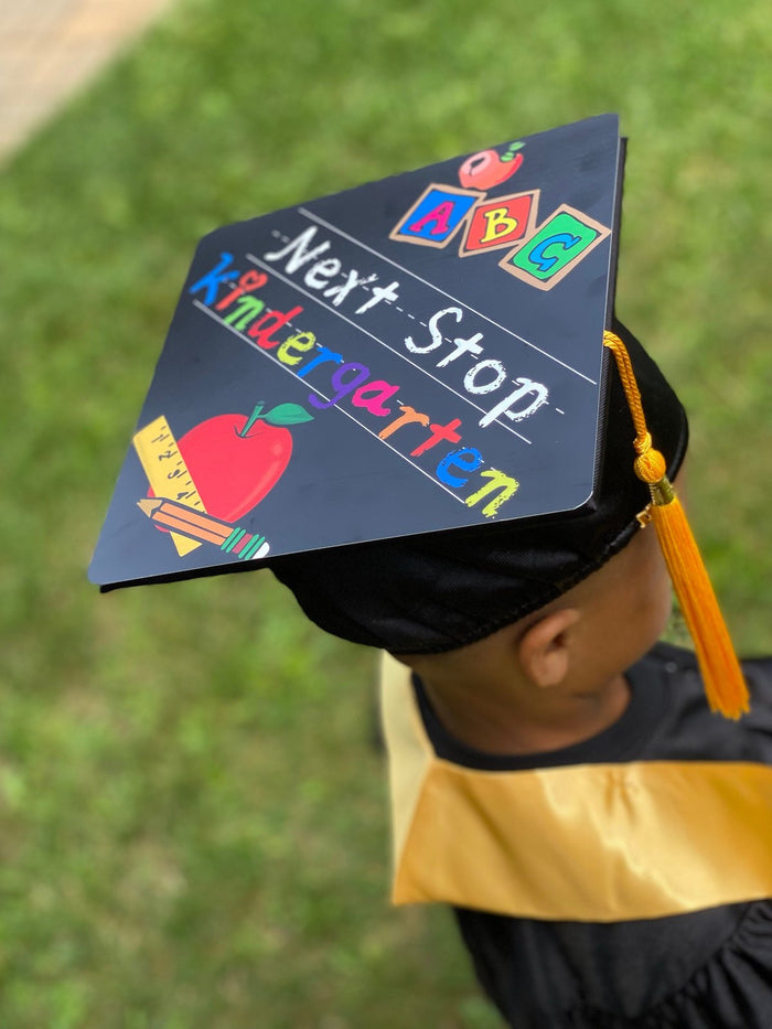 Child wearing Next Stop Kindergarten cap outdoors