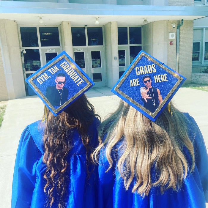 Two graduates wearing Gym Tan Graduate and Grads Are Here caps