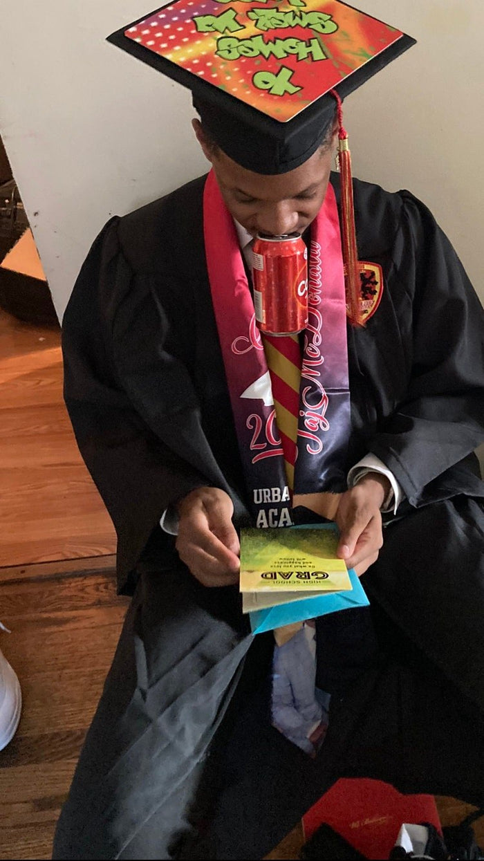 Graduate wearing Fresh Prince cap seated