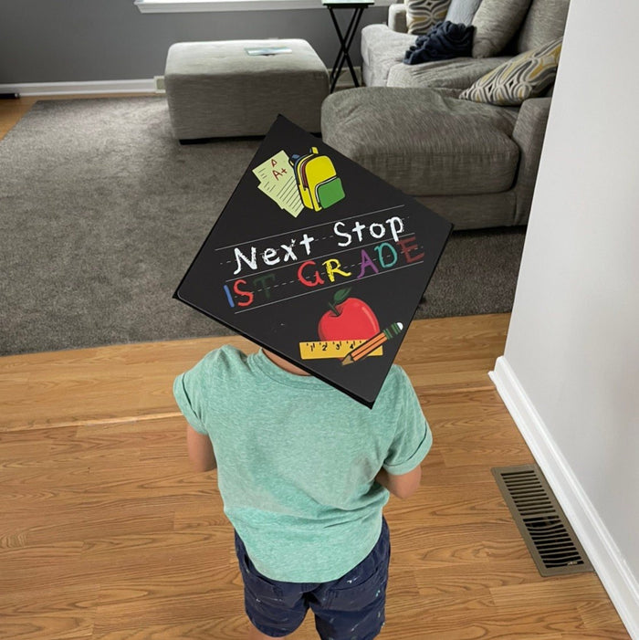 Child wearing Next Stop 1st Grade cap at home
