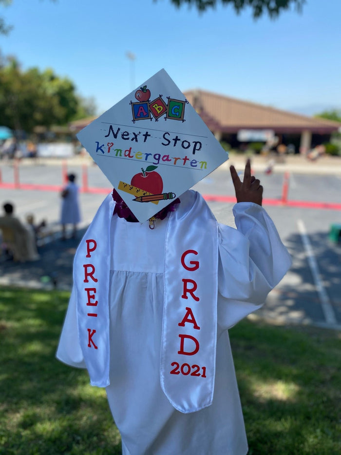 Child in Pre-K Grad gown wearing Next Stop Kindergarten cap