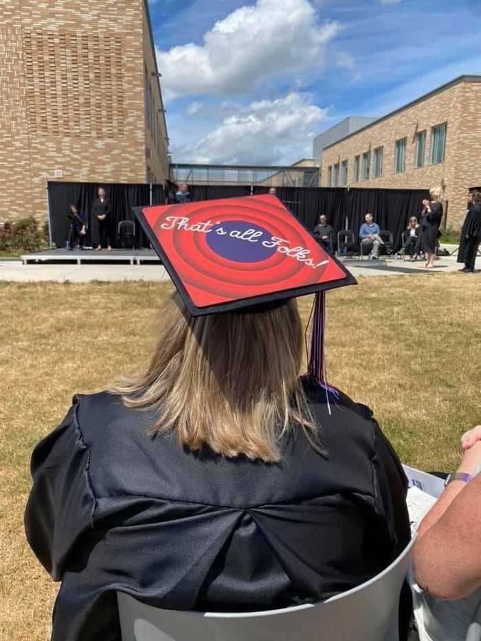 Graduate wearing Thats All Folks cap at outdoor ceremony