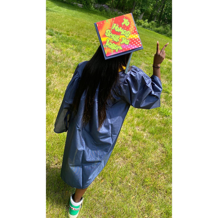 Graduate wearing Fresh Prince cap on lawn, back view