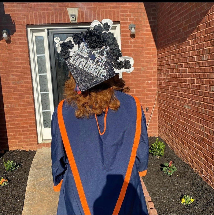 Graduate wearing black floral Graduate cap outside house