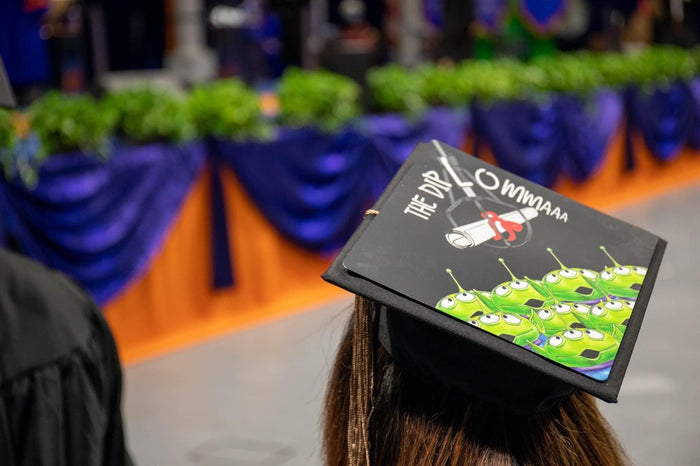 Graduate wearing Toy Story aliens cap at ceremony