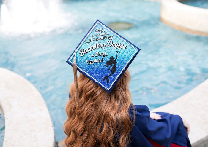 Graduate wearing mermaid Bachelors Degree cap by pool