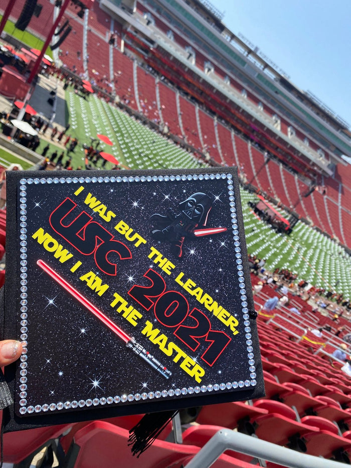 Hand holding USC Star Wars Master cap in stadium