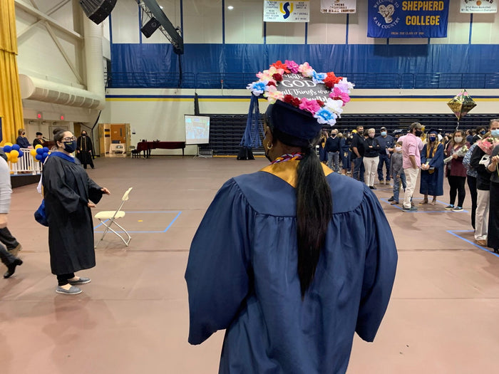 Graduate wearing flower cap in gymnasium ceremony