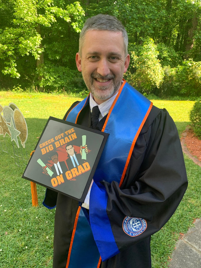 Graduate holding Big Brain On Brad Pulp Fiction cap