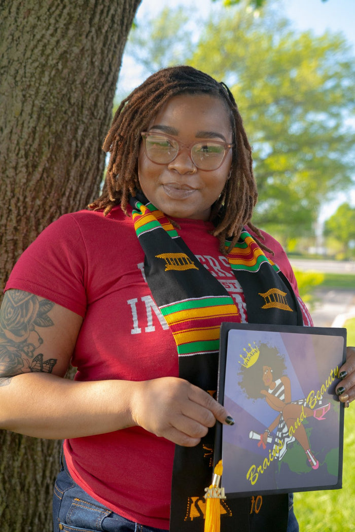 Graduate holding Brains And Beauty cap with 2021 tassel