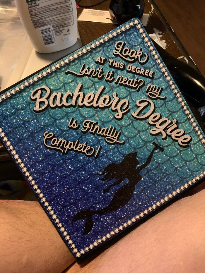 Mermaid Bachelors Degree topper on graduates lap