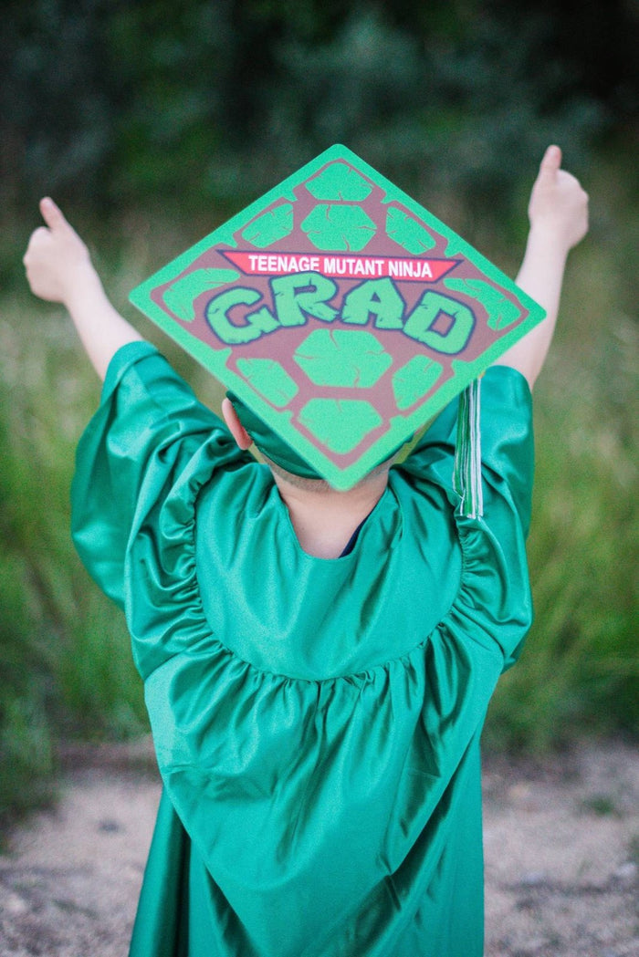 Child in green gown wearing TMNT Grad cap