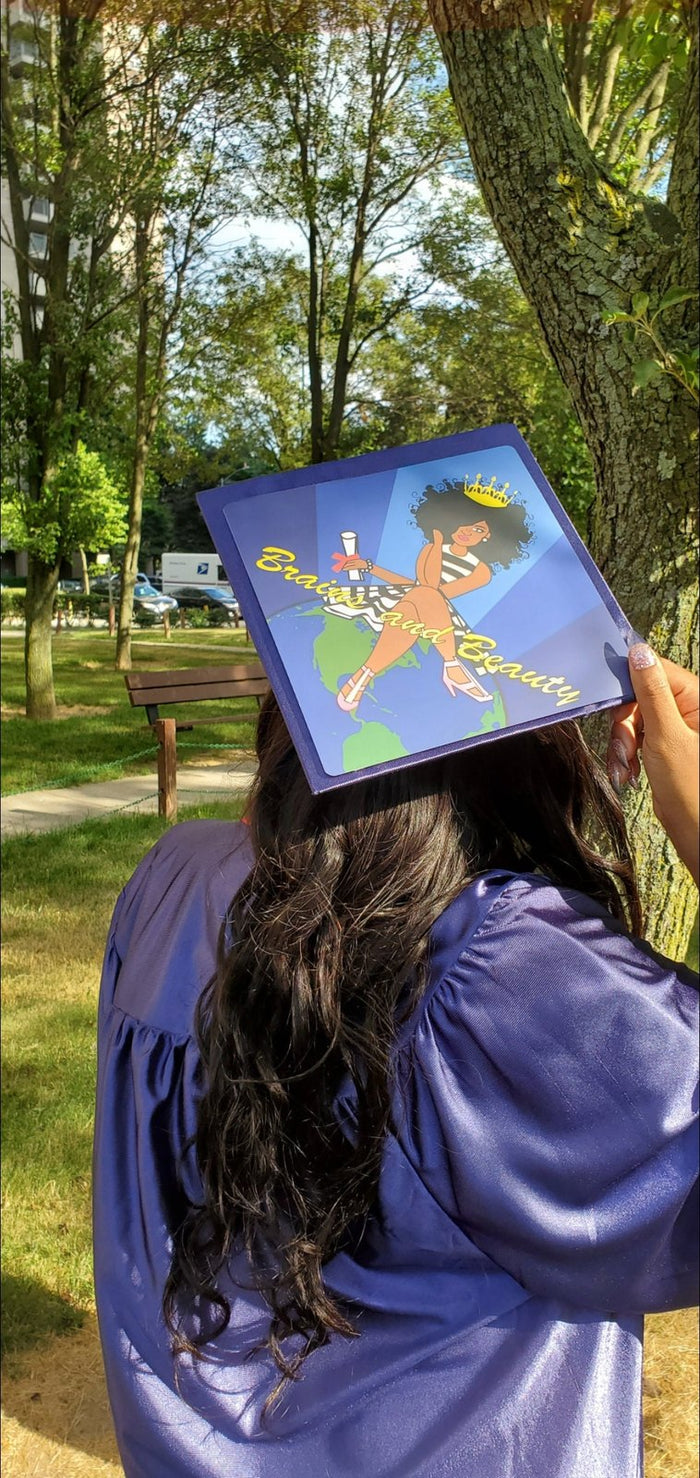 Graduate holding Brains And Beauty cap in park