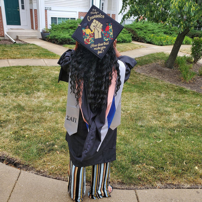 Graduate wearing BLM fist floral cap on sidewalk