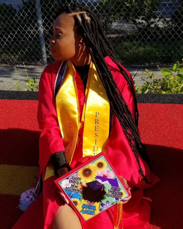 Young graduate holding sunflower photo cap on lap