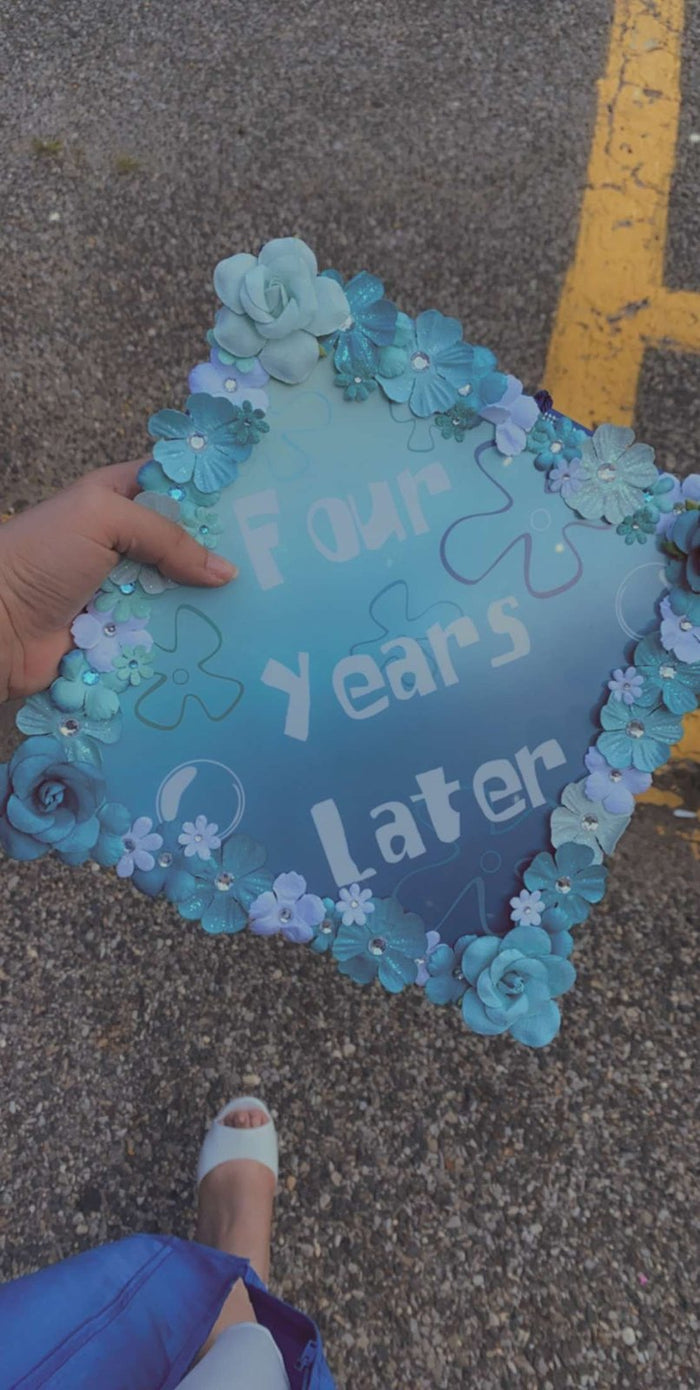 Hand holding floral Four Years Later topper outdoors