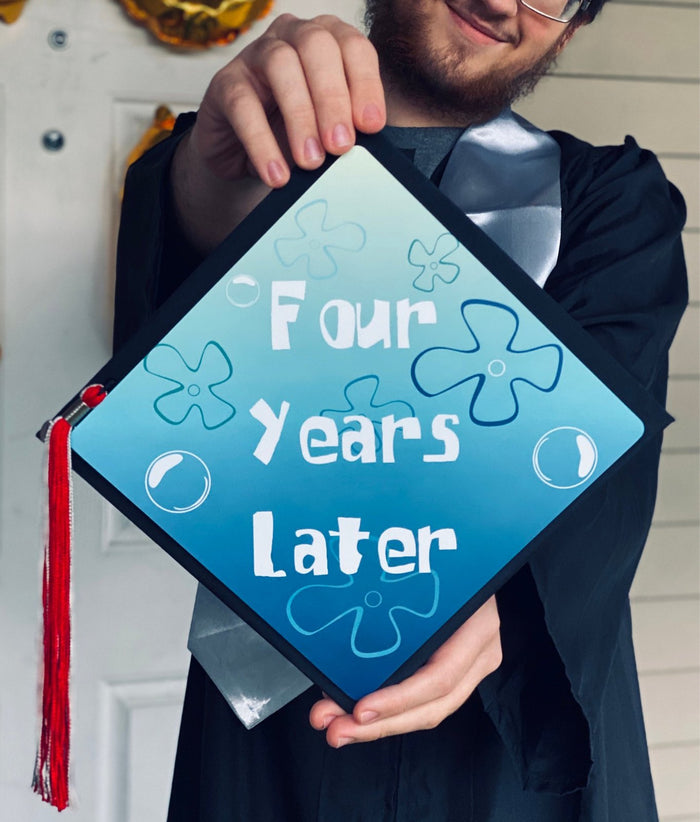 Graduate holding Four Years Later cap