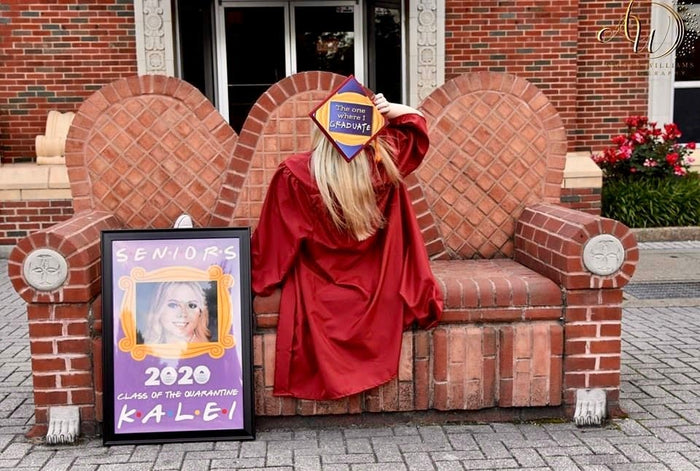Graduate in red gown holding Friends The One Where I Graduate cap