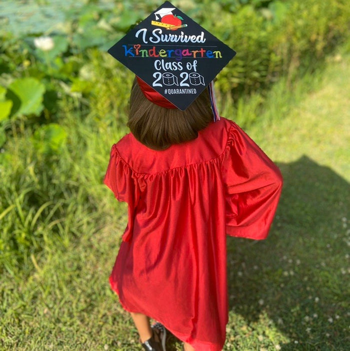 Child in red gown wearing I Survived Kindergarten cap