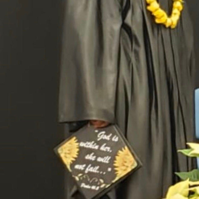 Graduate holding God Is Within Her sunflower cap