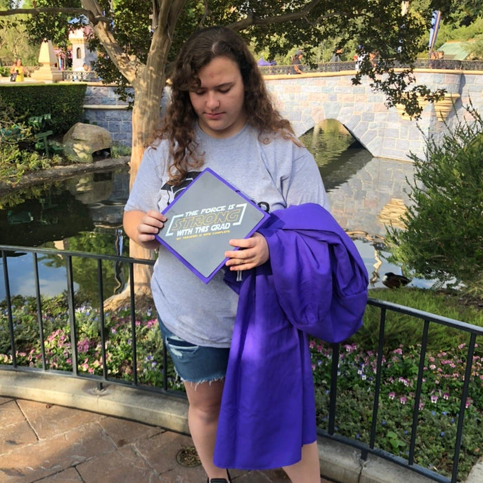 Graduate holding The Force Is Strong topper at Disneyland