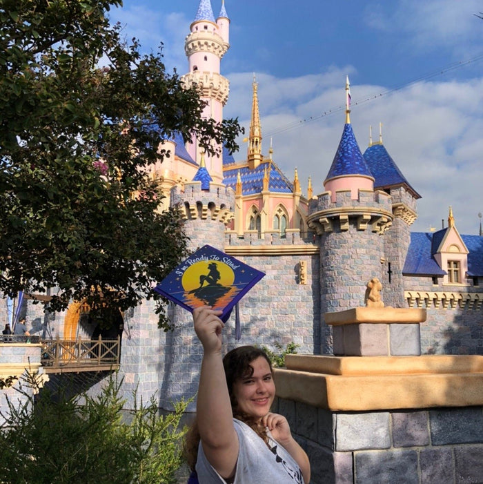 Graduate holding Ariel Im Ready To Stand cap at castle