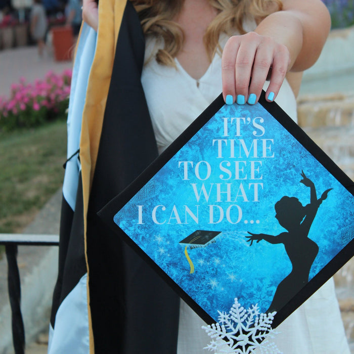 Graduate holding Tiana Its Time To See cap