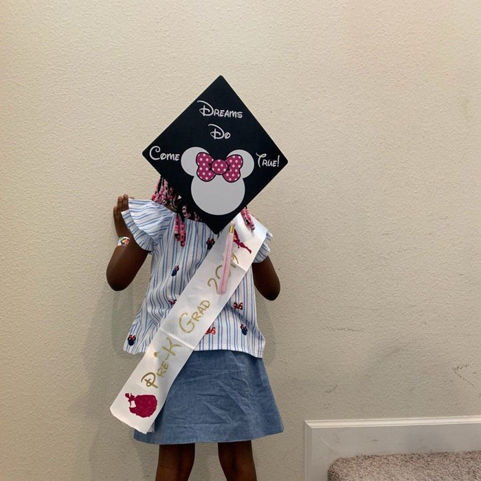 Young girl holding Minnie Dreams Do Come True cap