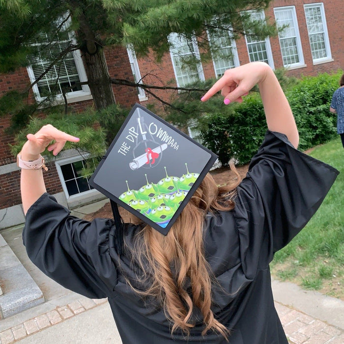 Graduate wearing Toy Story aliens cap pointing