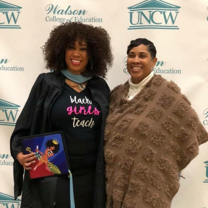 Graduate holding Wonder Woman topper at UNCW backdrop