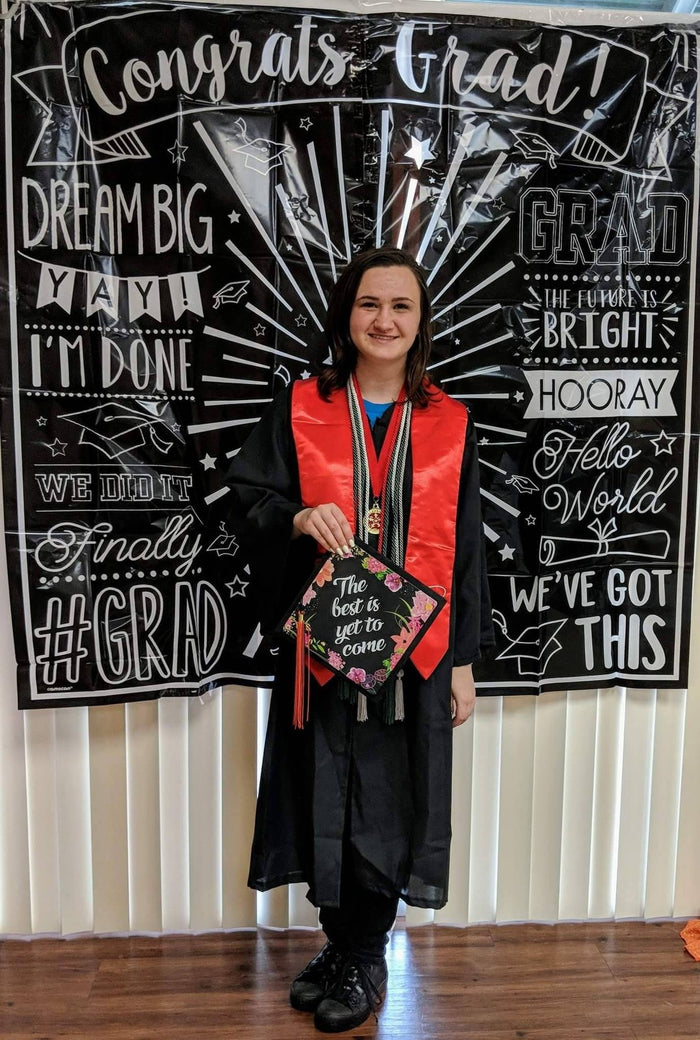 Graduate holding The Best Is Yet To Come cap at backdrop