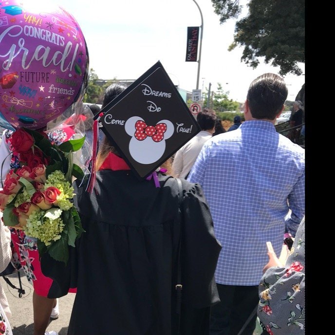 Graduate wearing Minnie cap with balloons and flowers