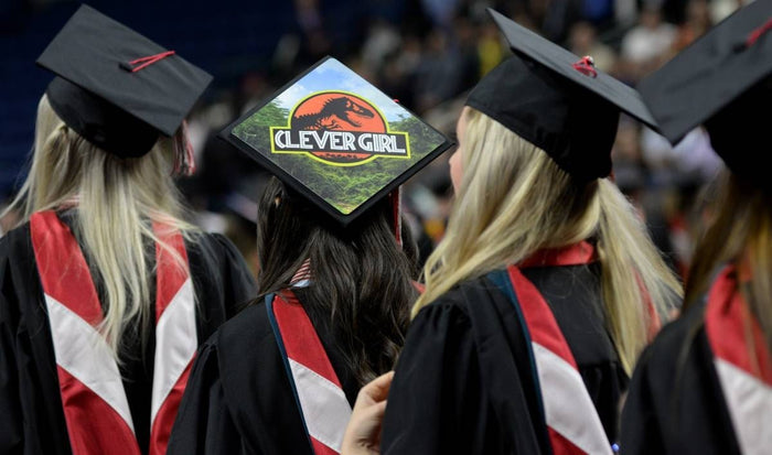 Graduate wearing Jurassic Clever Girl cap seated