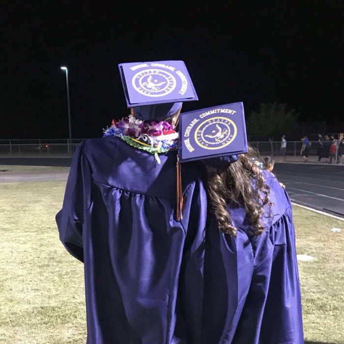 Two graduates wearing GCU seal caps at night