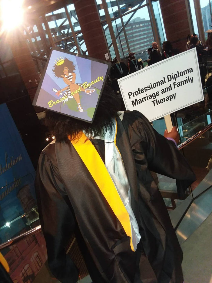 Graduate wearing Brains And Beauty cap indoors