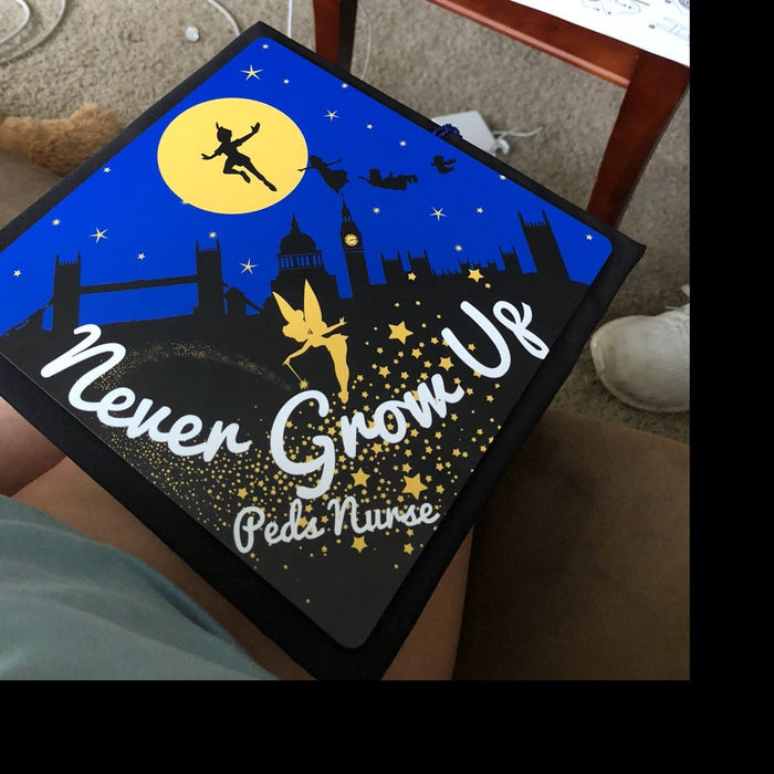 Peter Pan Never Grow Up topper on graduates lap