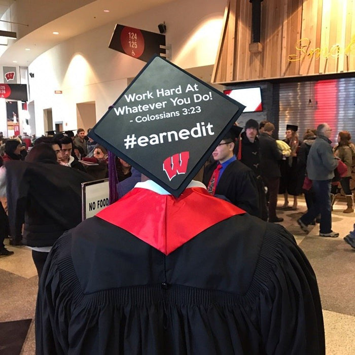 Graduate wearing Wisconsin Earnedit cap in lobby