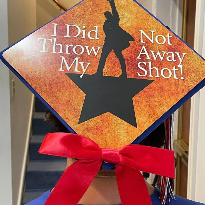 Graduate wearing Hamilton Not Throw Away My Shot cap with red bow