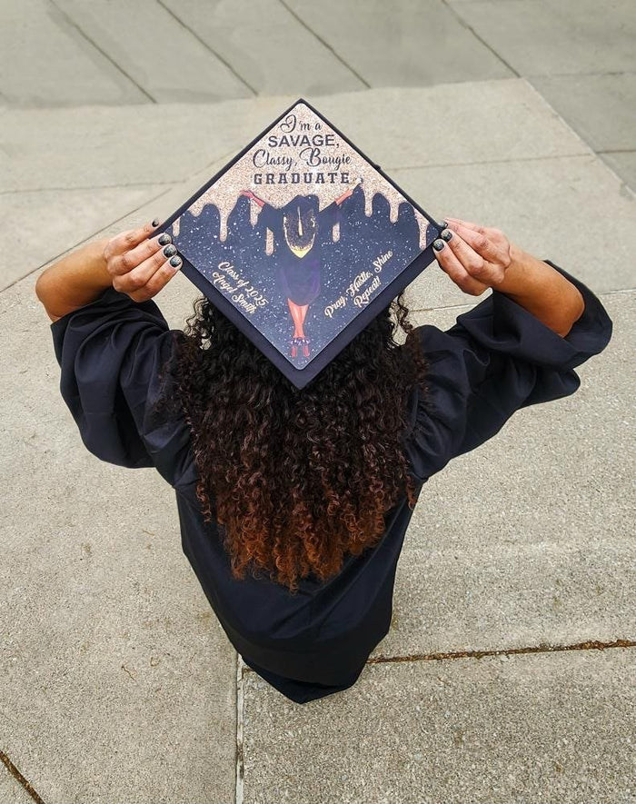 Graduate holding Savage Classy Bougie NYC cap over head