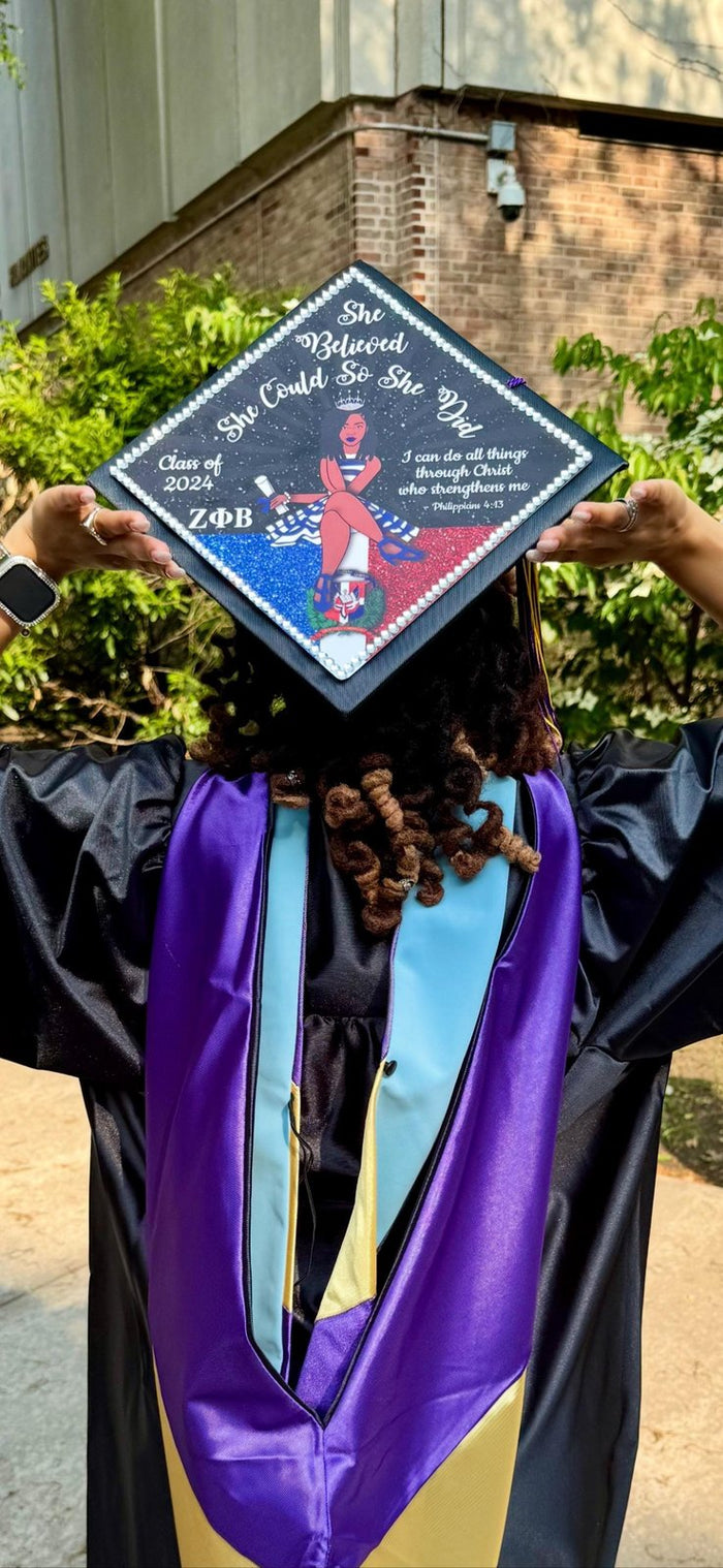 Graduate holding Wonder Woman She Believed cap over head