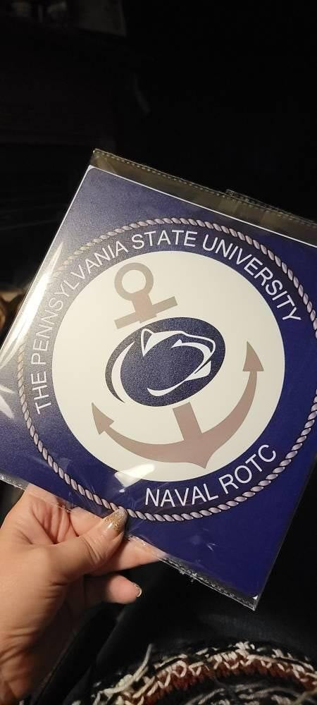 Hand holding Penn State Naval ROTC topper