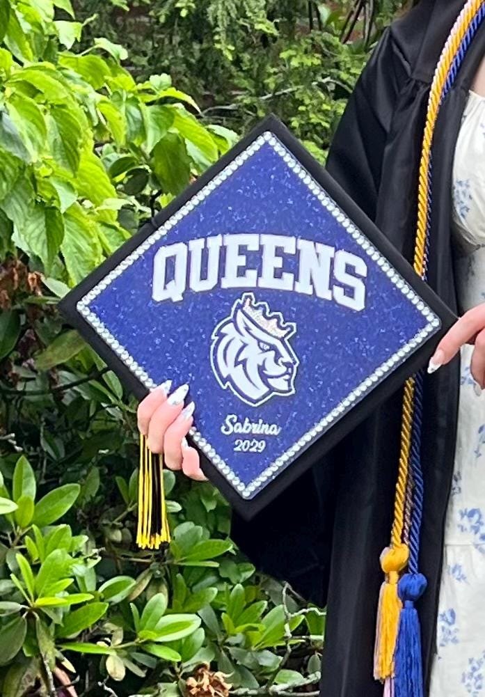 Graduate holding Queens Sabrina cap