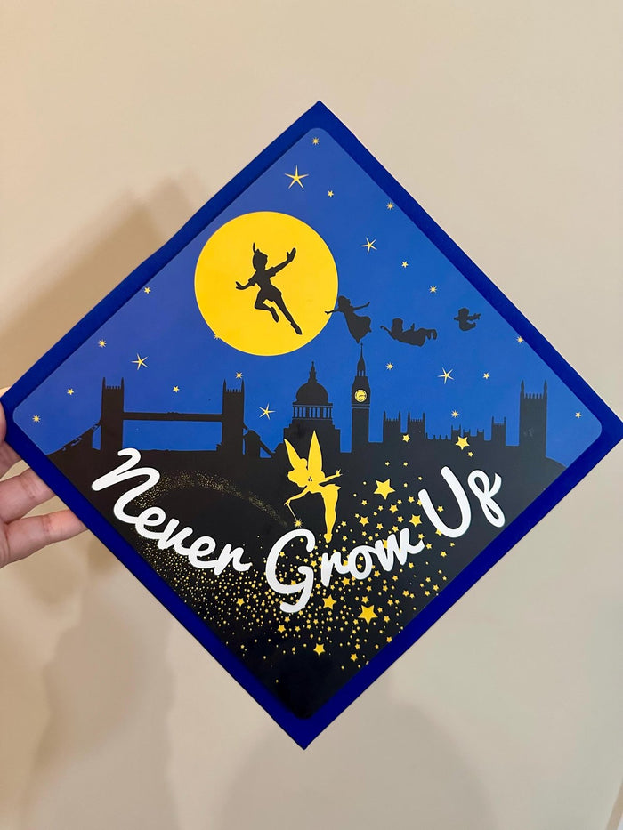 Hand holding Peter Pan Never Grow Up topper