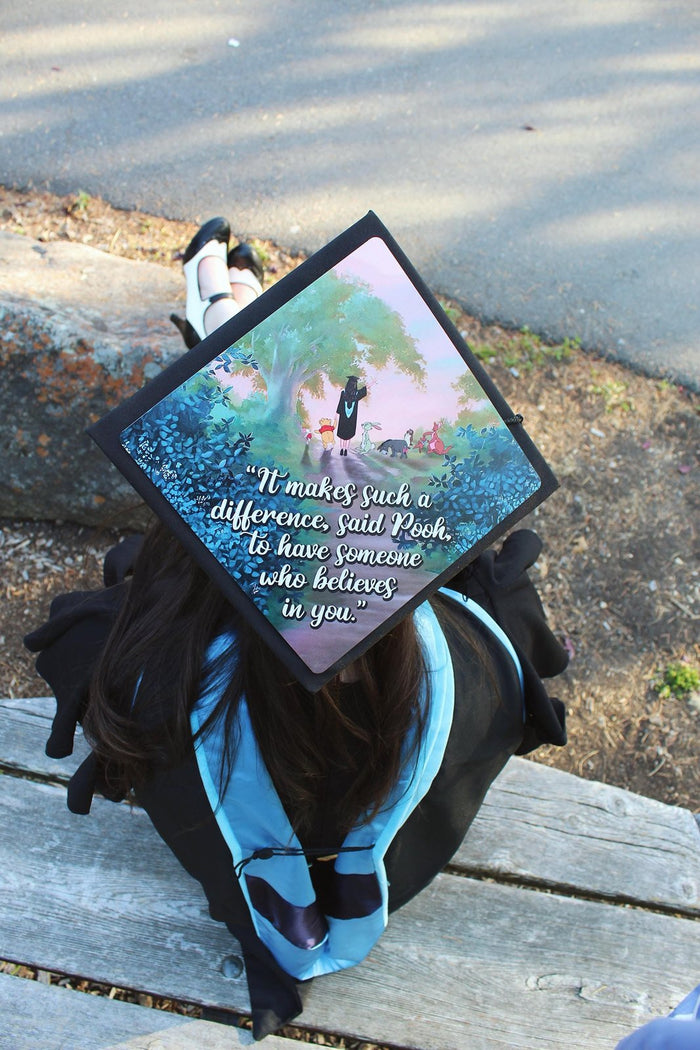 Graduate wearing Pooh It Makes Such A Difference cap on bench
